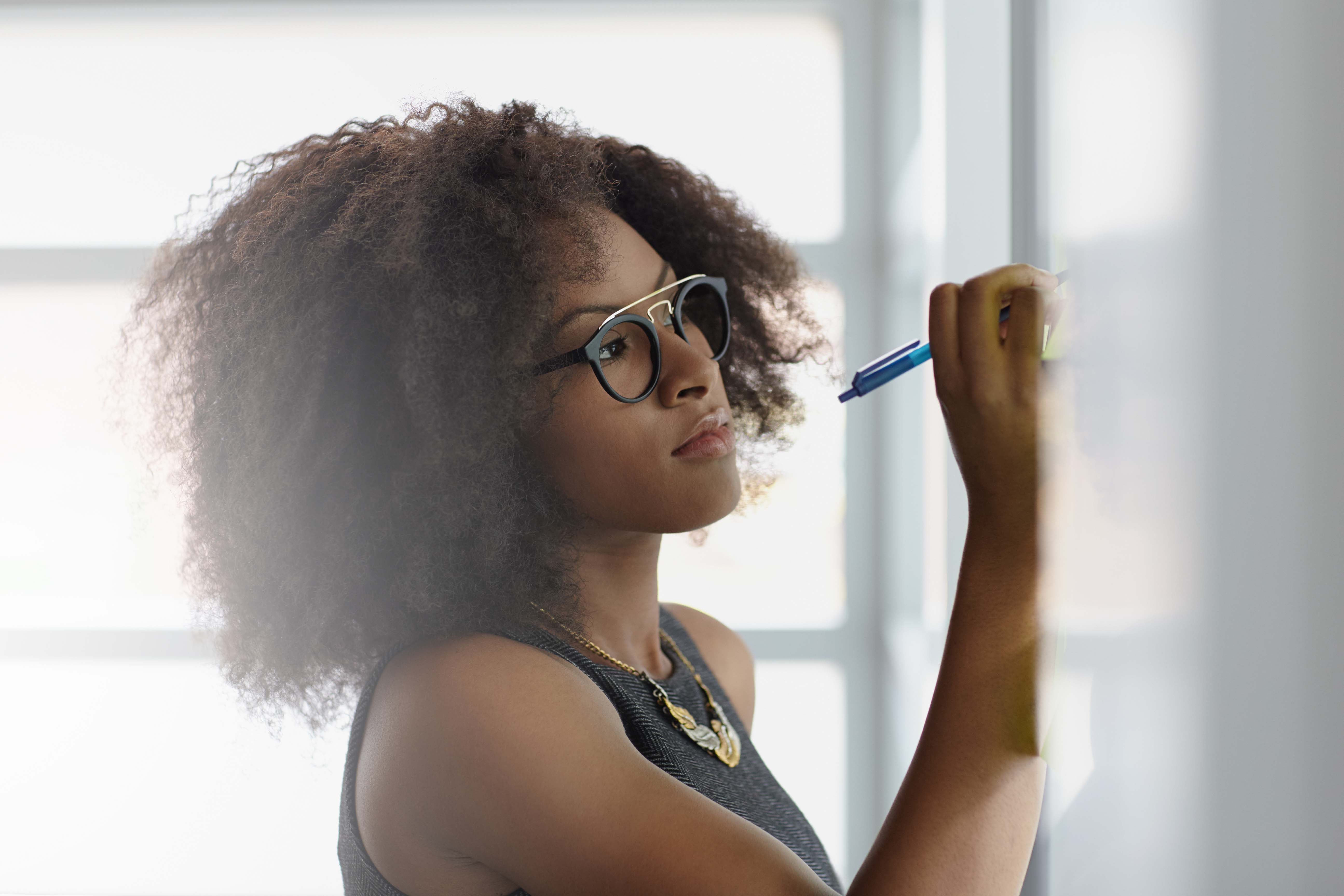 Une femme avec lunettes en train d'écrire sur un tableau