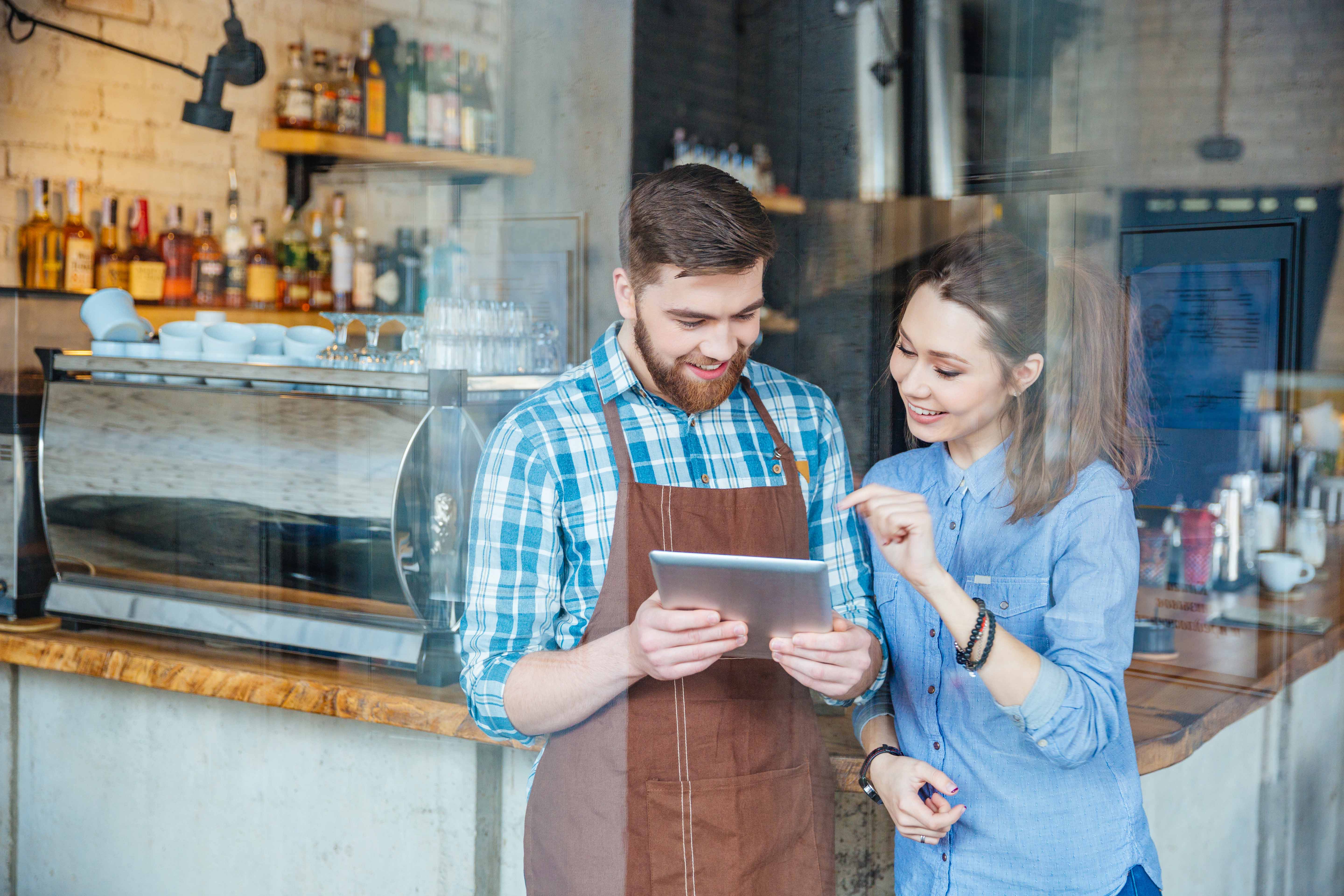 Un serveur dans un bar restaurant montrant quelque chose sur une tablette à une femme